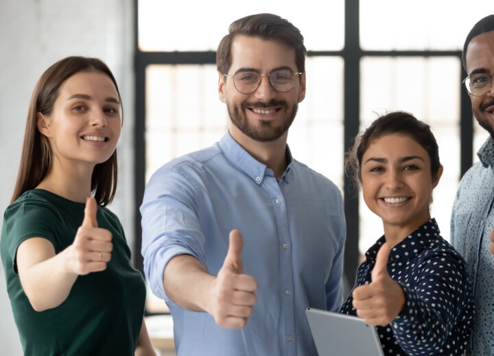 Proud multi ethnic business team young people showing thumbs up looking at camera. Smiling professional corporate staff group diverse happy four employees photo shoot. Human resource, advance concept